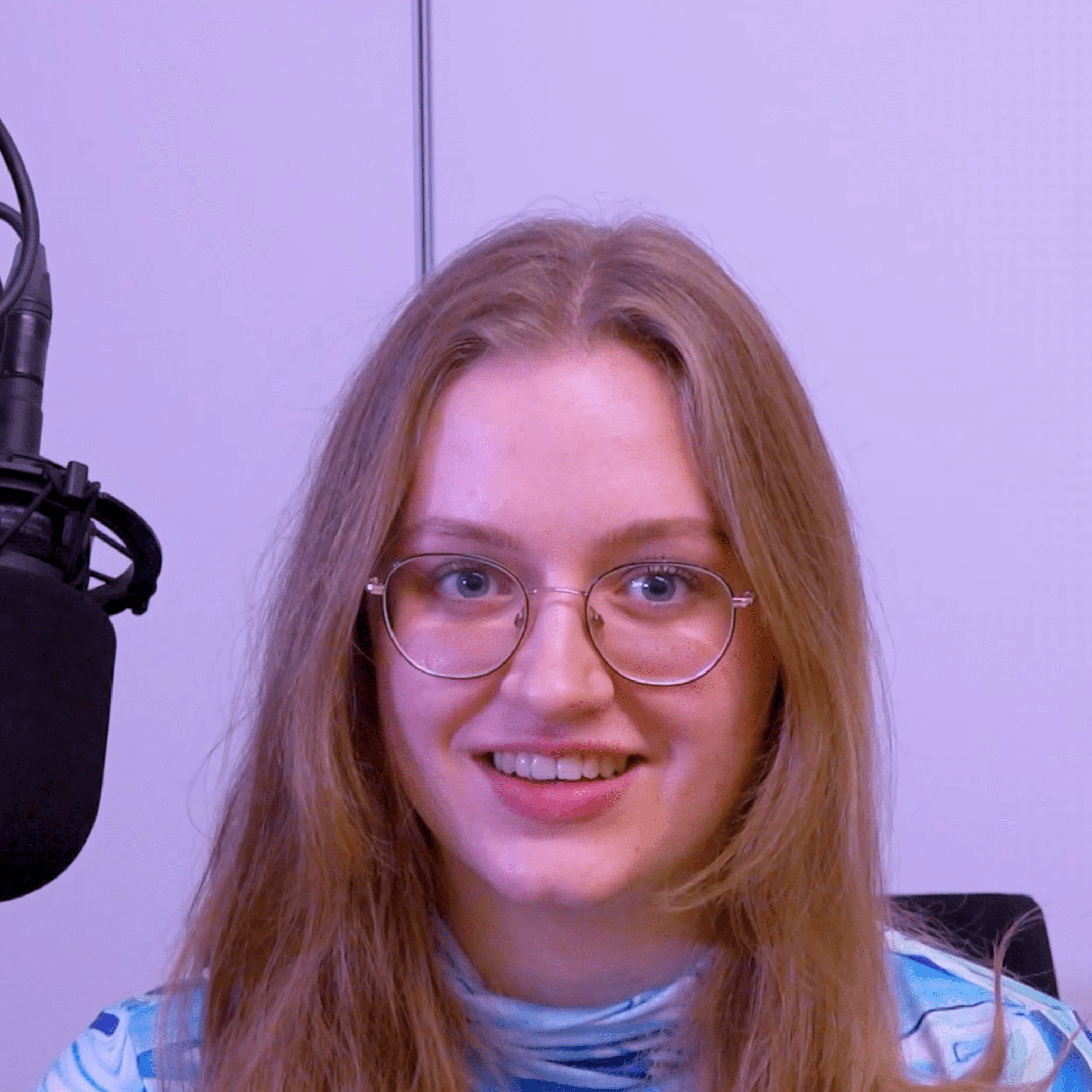 Amalja sitzt in ihrem Podcast-Studio und lächelt.